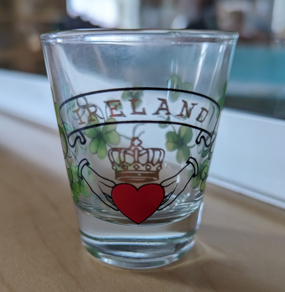 A shot glass with shamrocks, heart, crown, "Ireland" banner