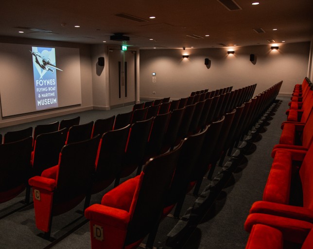 Empty theatre with red seats facing a screen at Flying Boat Museum Foynes.