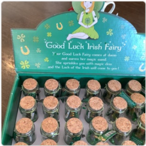 bottles with “Good Luck Fairy” labels by a green decorative sign.
